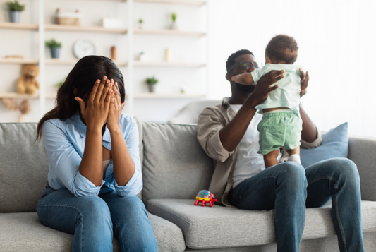 Tired African American mom crying, dad playing with kid